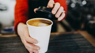 Putting a lid on a coffee cup to go