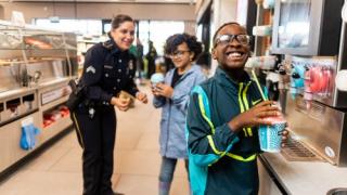 Police officer and two kids getting Slurpees at 7-Eleven