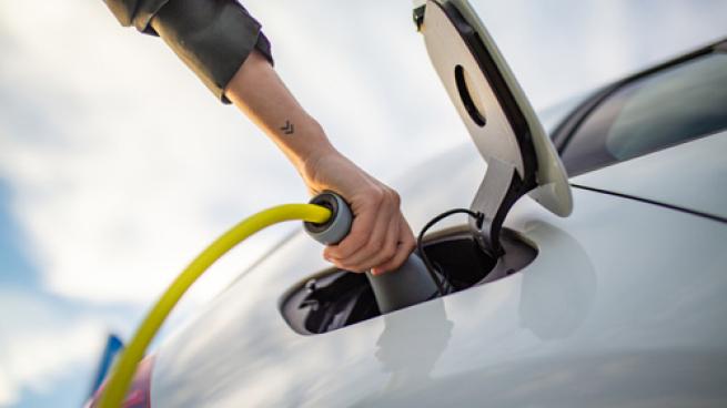 A person charging an electric vehicle