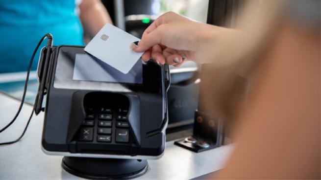 A person tapping a debit card at checkout