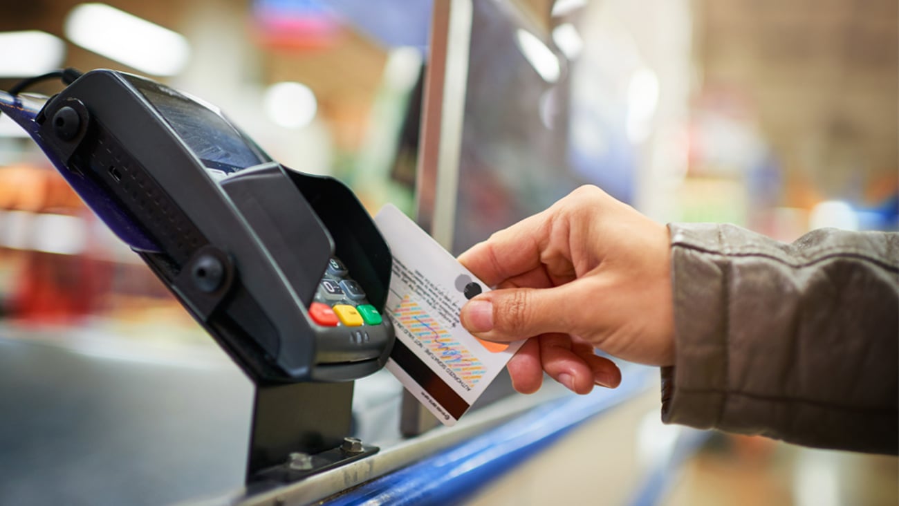 A person swiping a debit card at retail