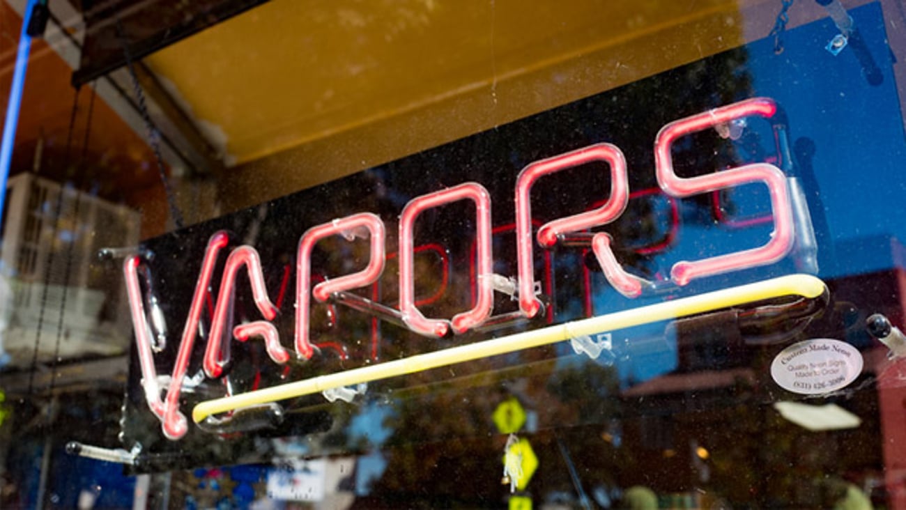 A neon Vapor sign in the window of a store