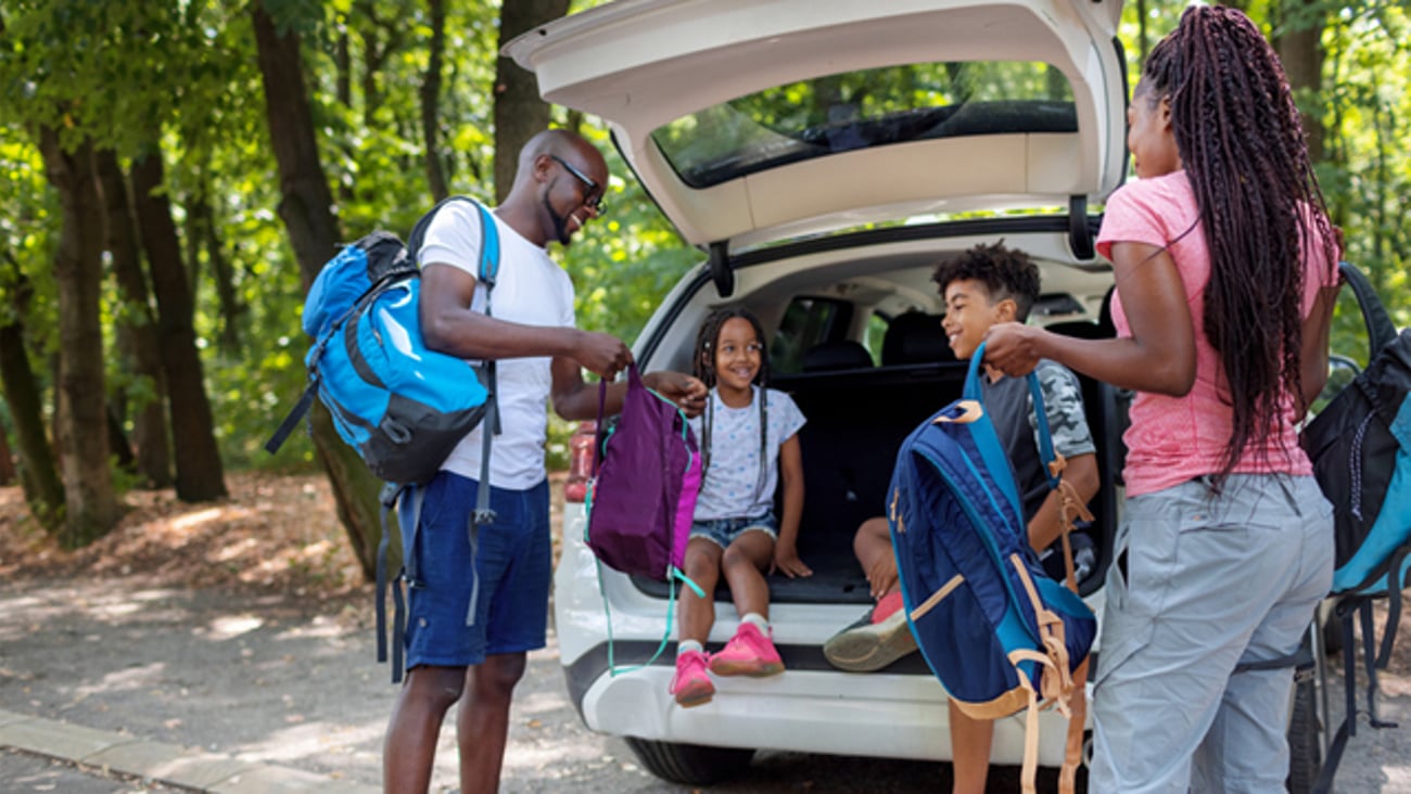 A family of four unpacking a car in the forest