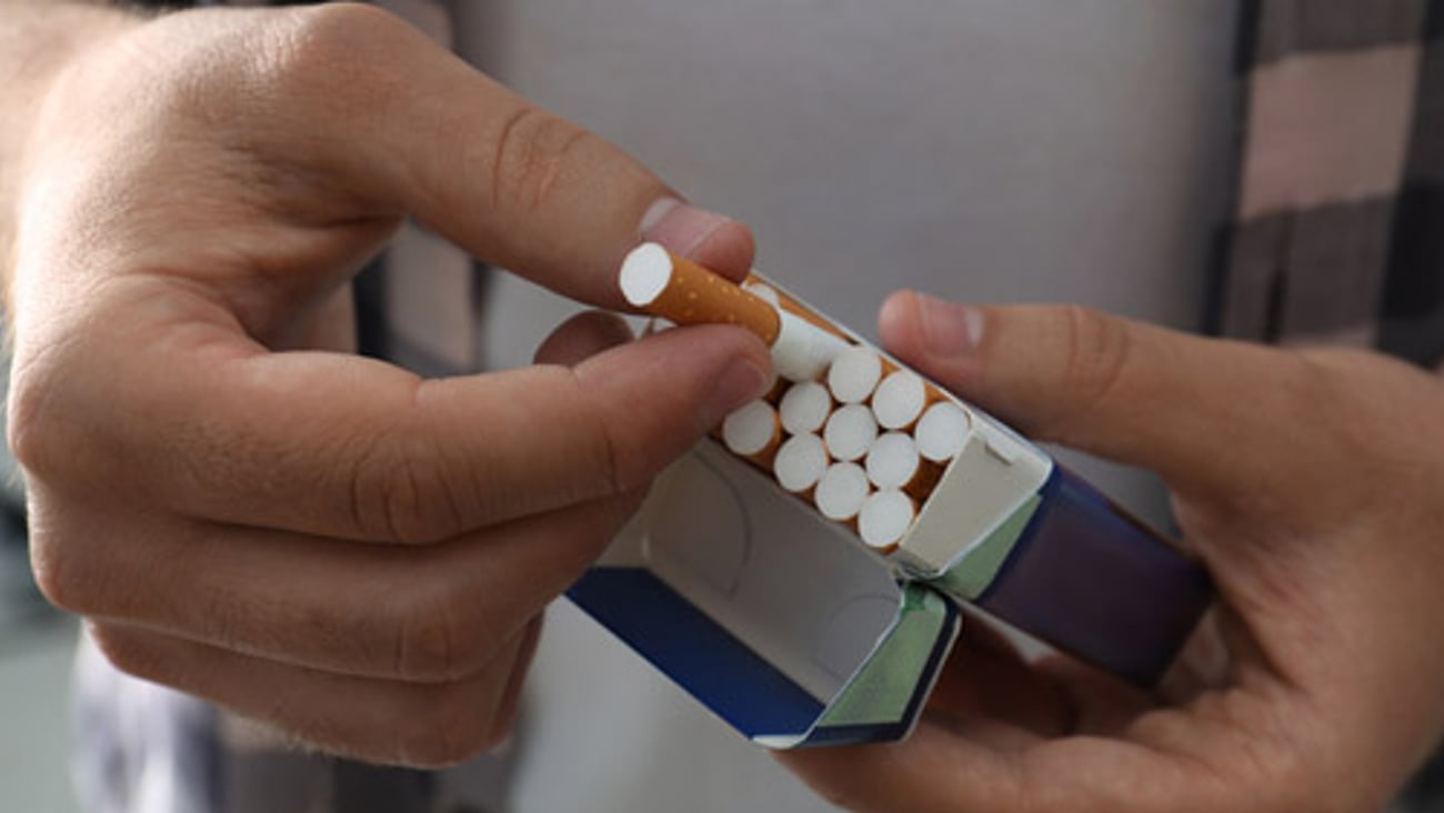 A man pulling a cigarette from a cigarette pack