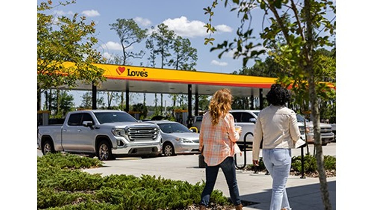 Two women walking in front of cars parked at a Love's