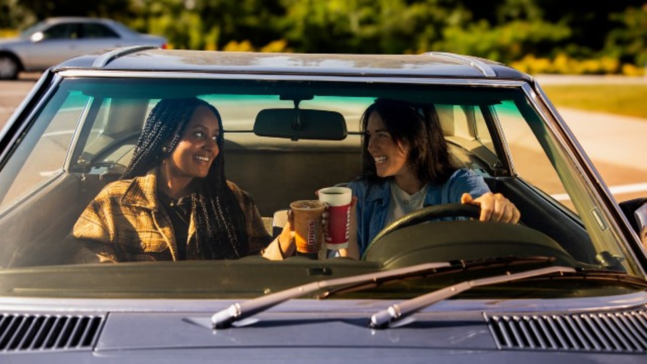 Two women sitting in a car and drinking Pilot coffee