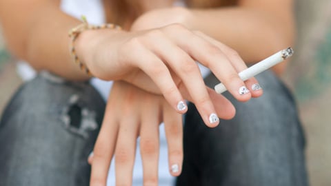 A teenager holding a cigarette