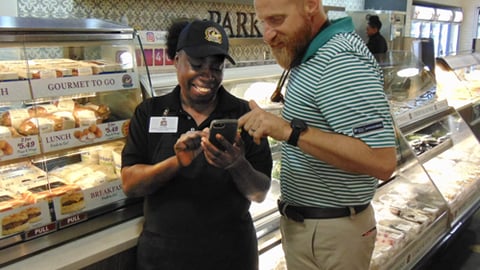 Parker’s Chief Human Resources Officer Corey McClimans shows Lucille Washington, deli associate, how to use the new DailyPay technology.