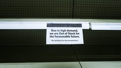 Out of stock notice on an empty store shelf