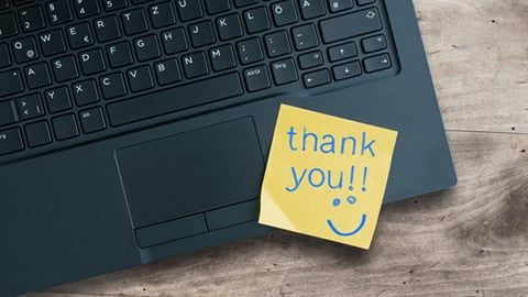 A thank you sticky note on a keyboard