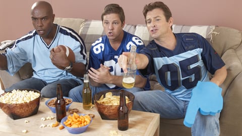 Three football fans eating snacks and watching a game