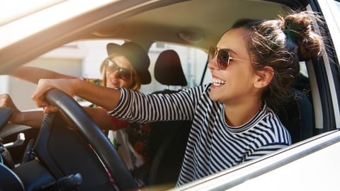 Two women driving in a car during the summer