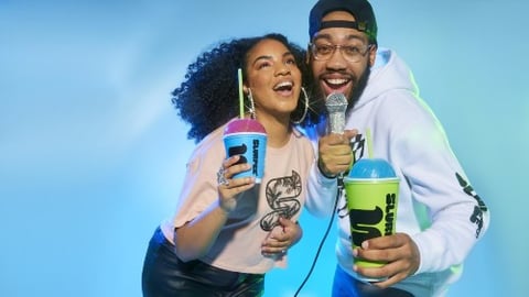 Couple singing into microphone while holding Slurpees