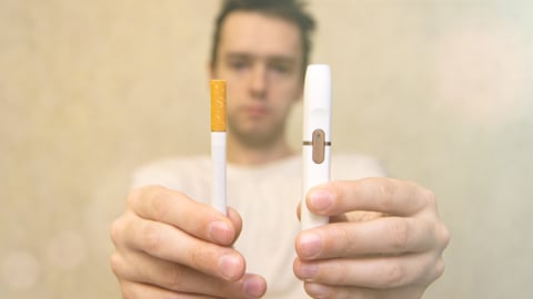 A man holding a cigarette and a vapor product