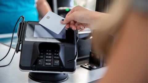 A person tapping a debit card at checkout