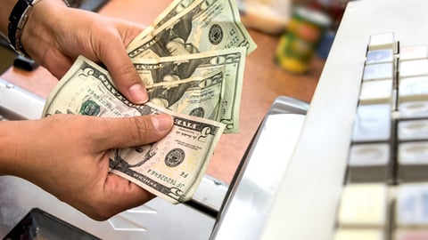A consumer handles money at checkout. 