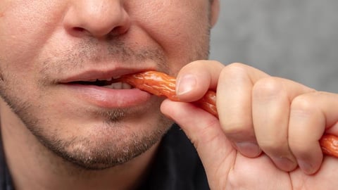 A man eating a piece of beef jerky