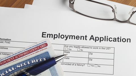 A paper job application with eye glasses,  pen and a social security card