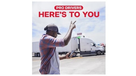 Truck driver giving a peace sign in front of a tractor trailer