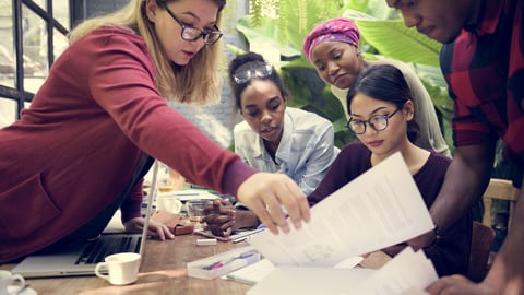 Group of diverse women doing work around a table in an office