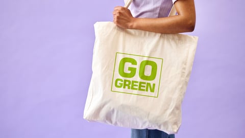 Woman carrying a reusable shopping bag with the words Go Green on it 