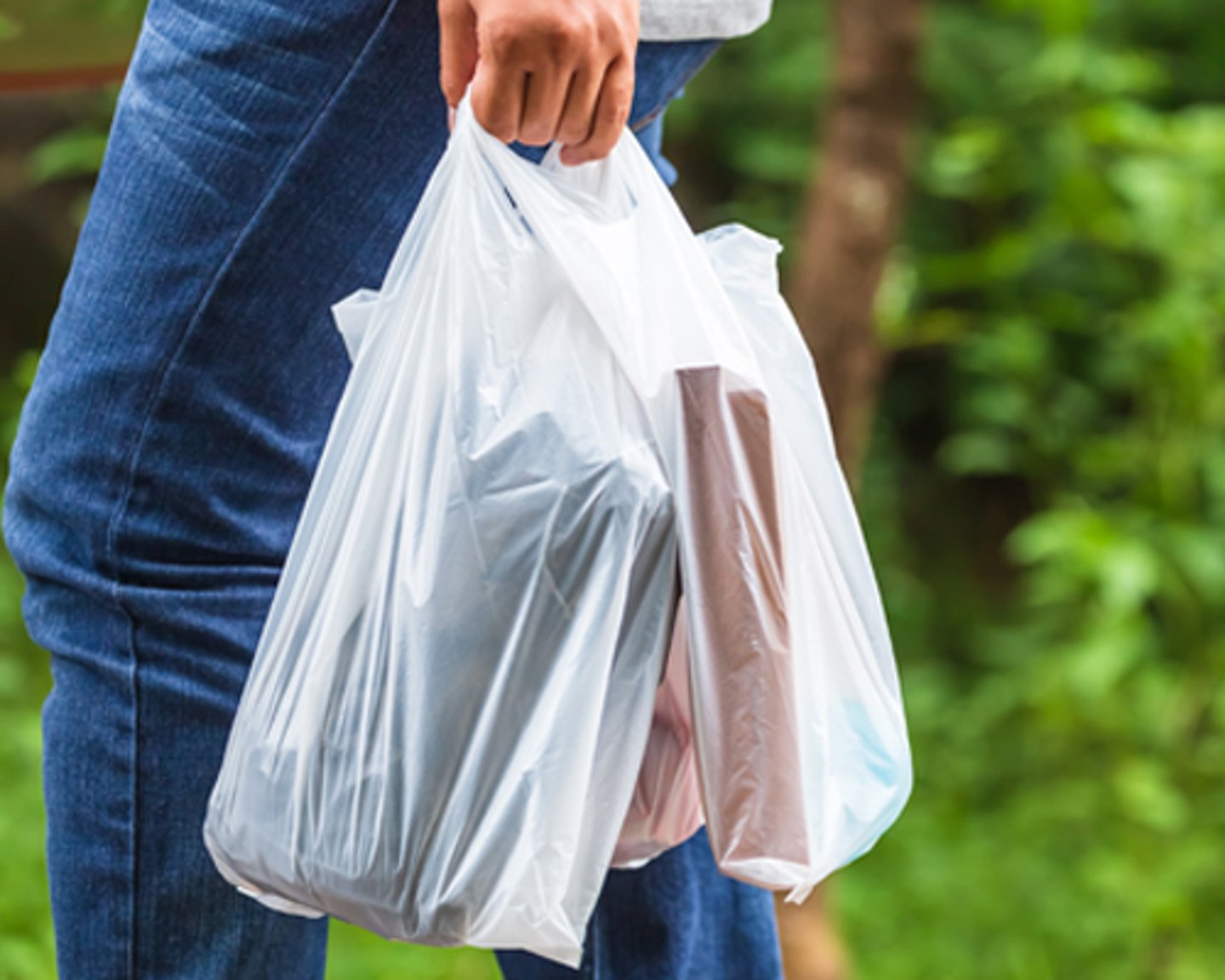 A consumer carrying plastic shopping bags