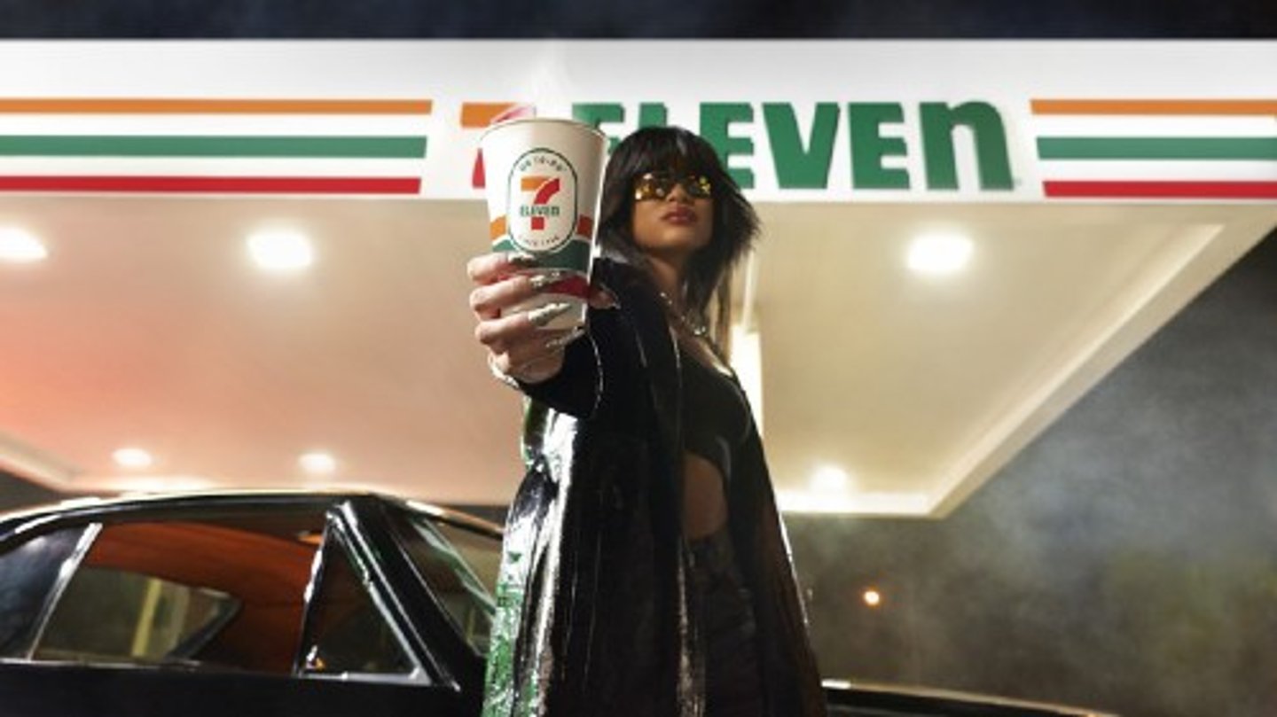 Woman holding 7-Eleven coffee cup toward camera