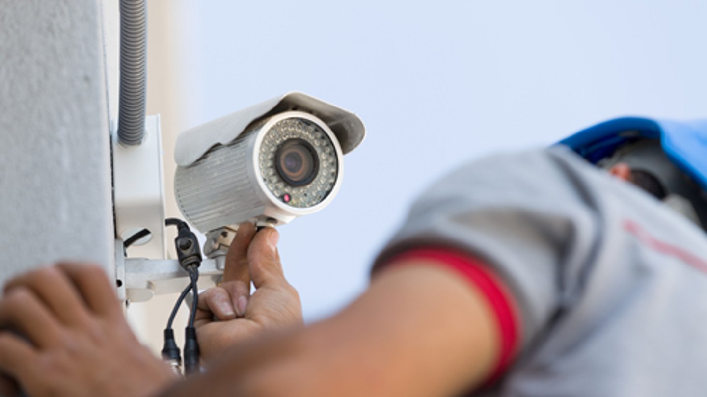 A man installing a security camera outside a store