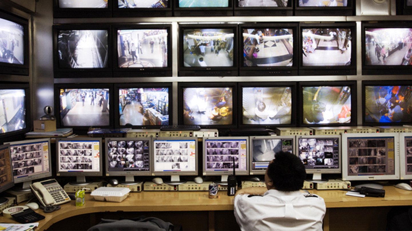 A security guard sitting in front of surveillance video screens