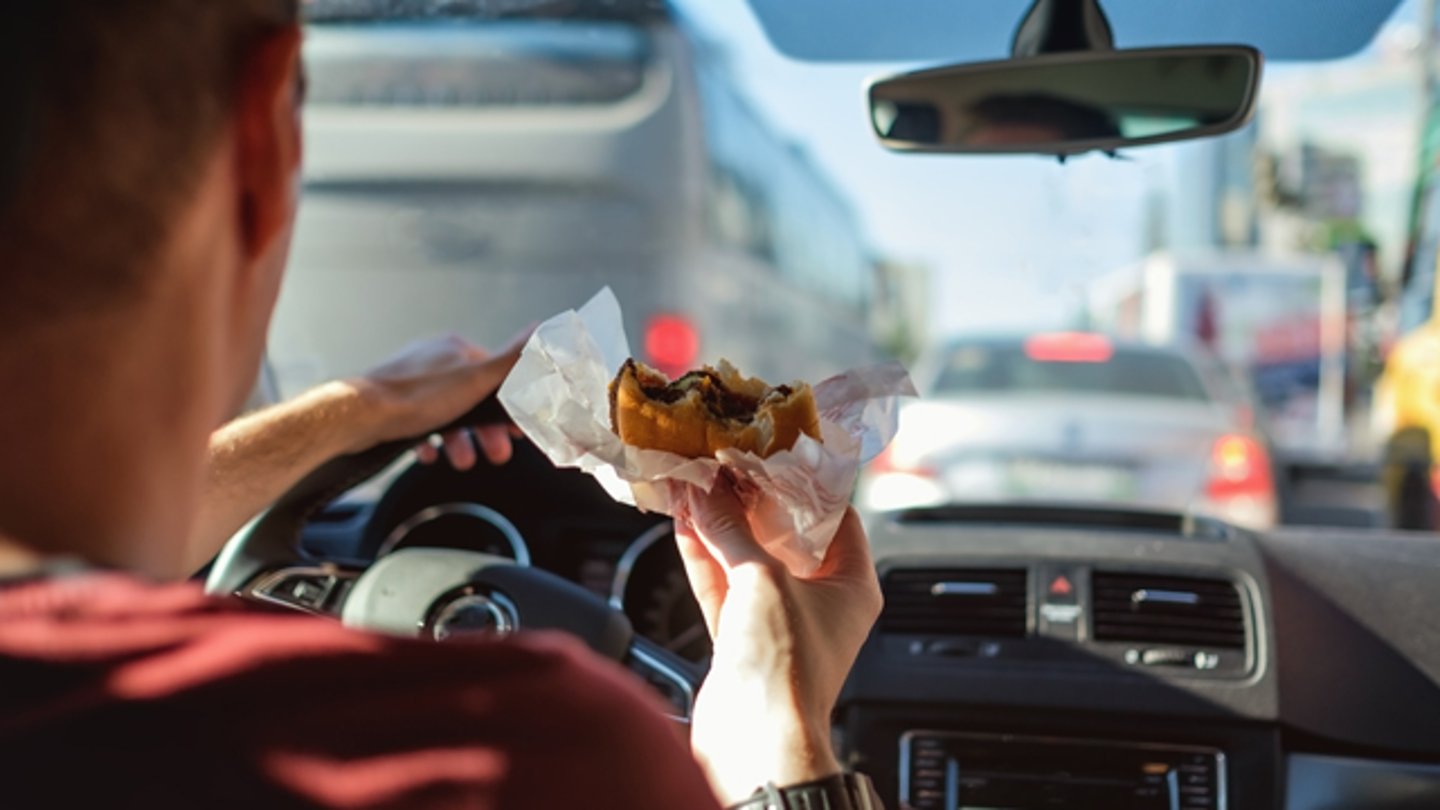 A male driver eating a burger