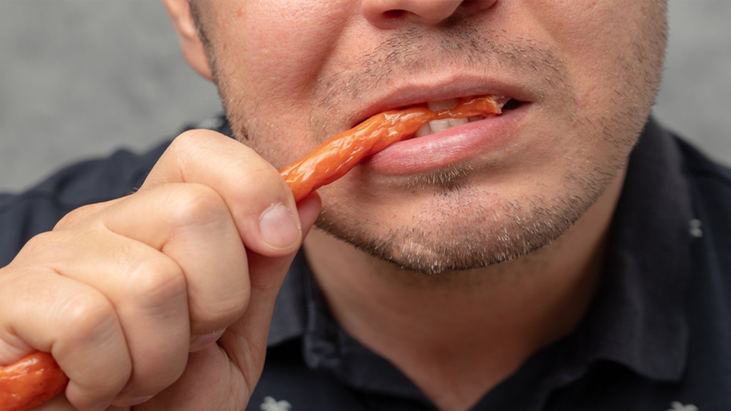man biting into meat stick