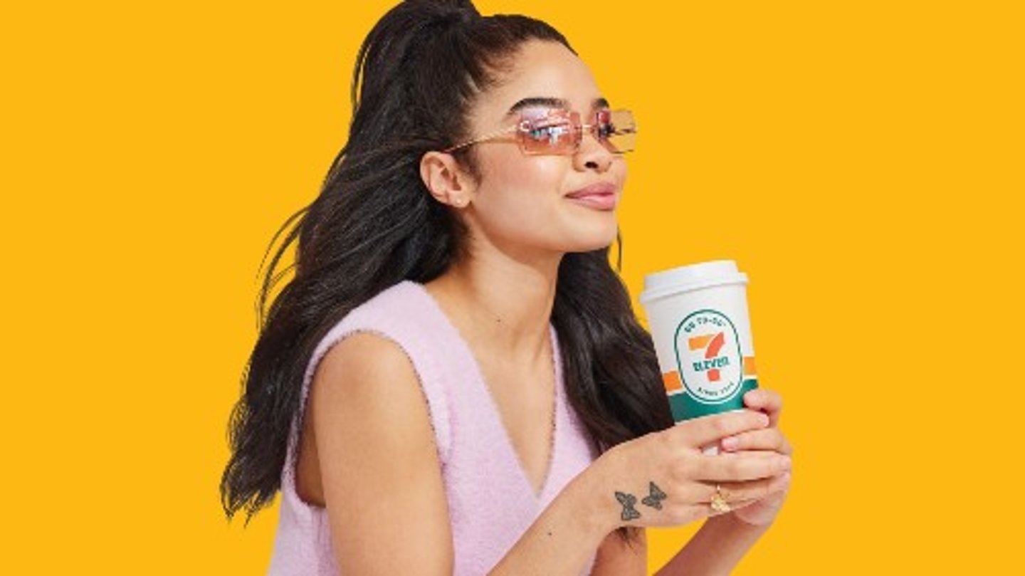 A woman in sunglasses holding a 7-Eleven coffee cup