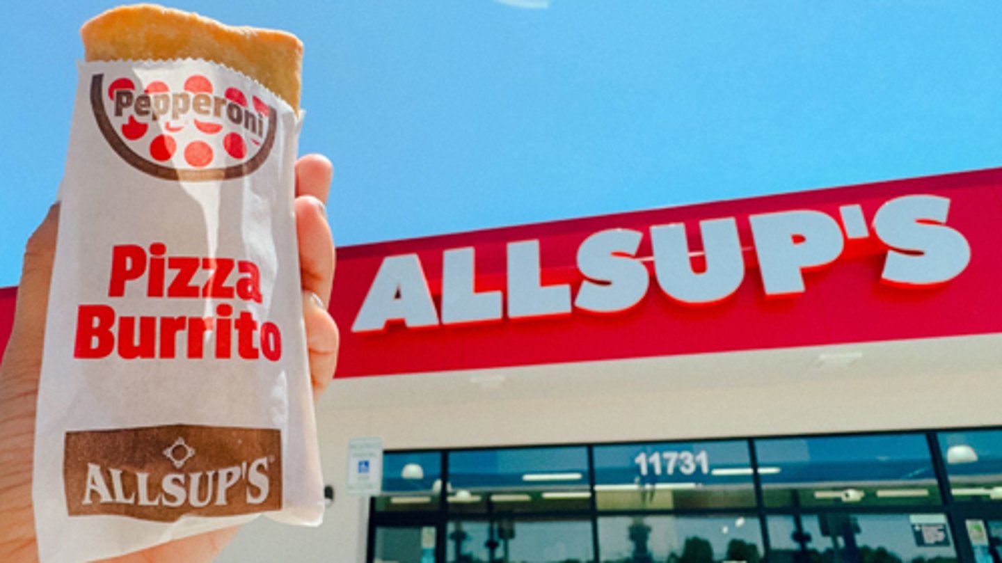 A customer holding a Allsup's Pepperoni Pizza Burrito outside a c-store