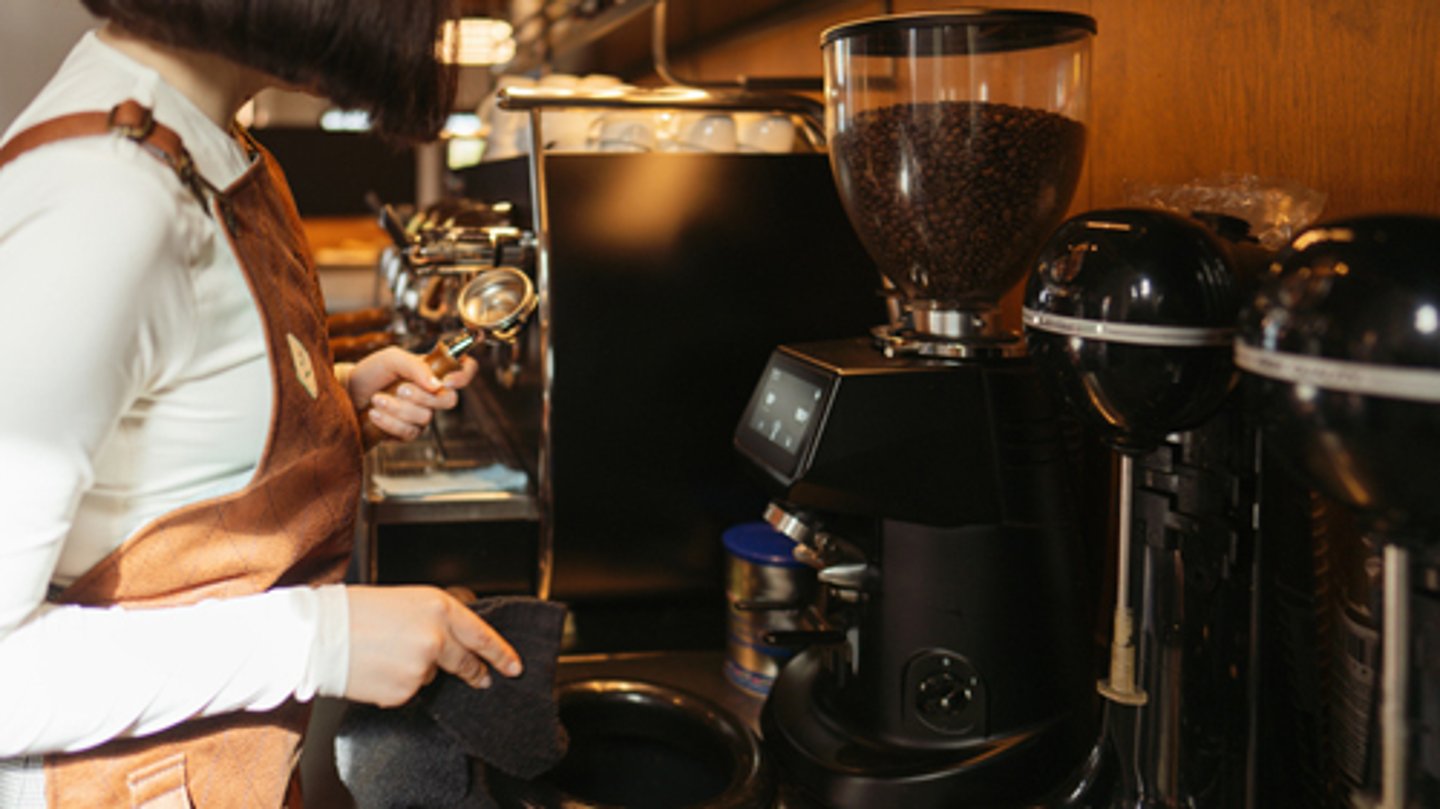 A person using a bean-to-cup coffee machine