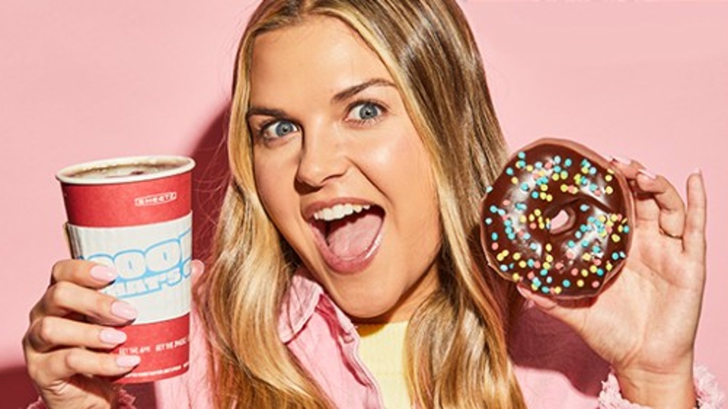 Excited woman holding a coffee and chocolate donut 