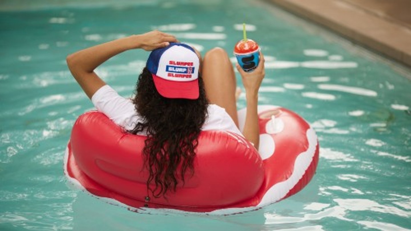 Woman sitting in a pool floaty while holding a Slurpee 