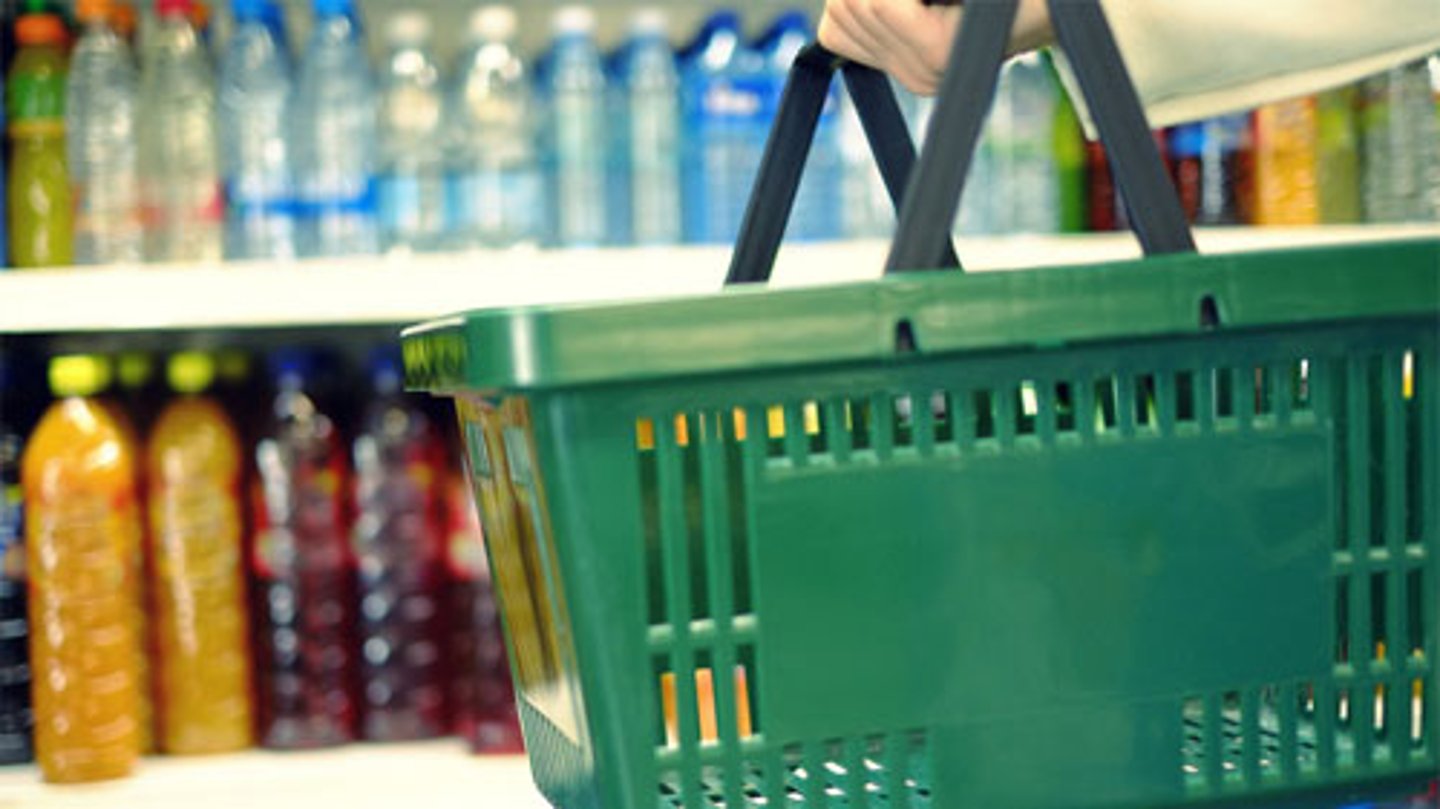 A customer holding a shopping basket looking at beverages