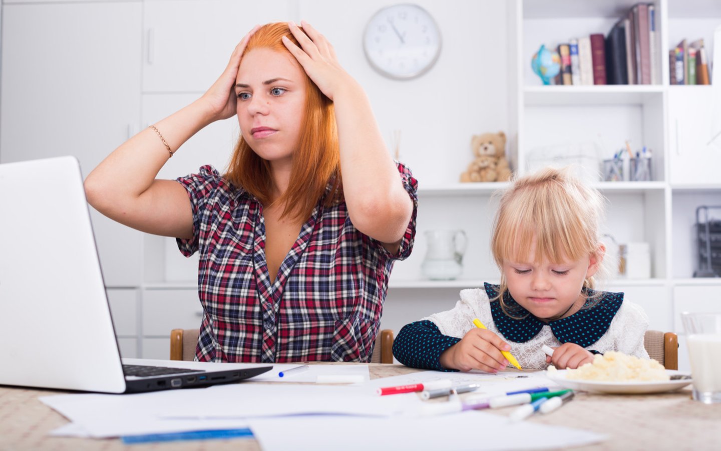 frustrated mother looking in computer with daughter drawing next to her ; Shutterstock ID 512452684